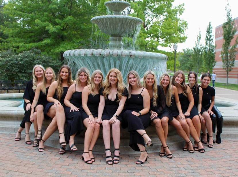 The executive board of Phi Mu posing at a fountain on campus.
